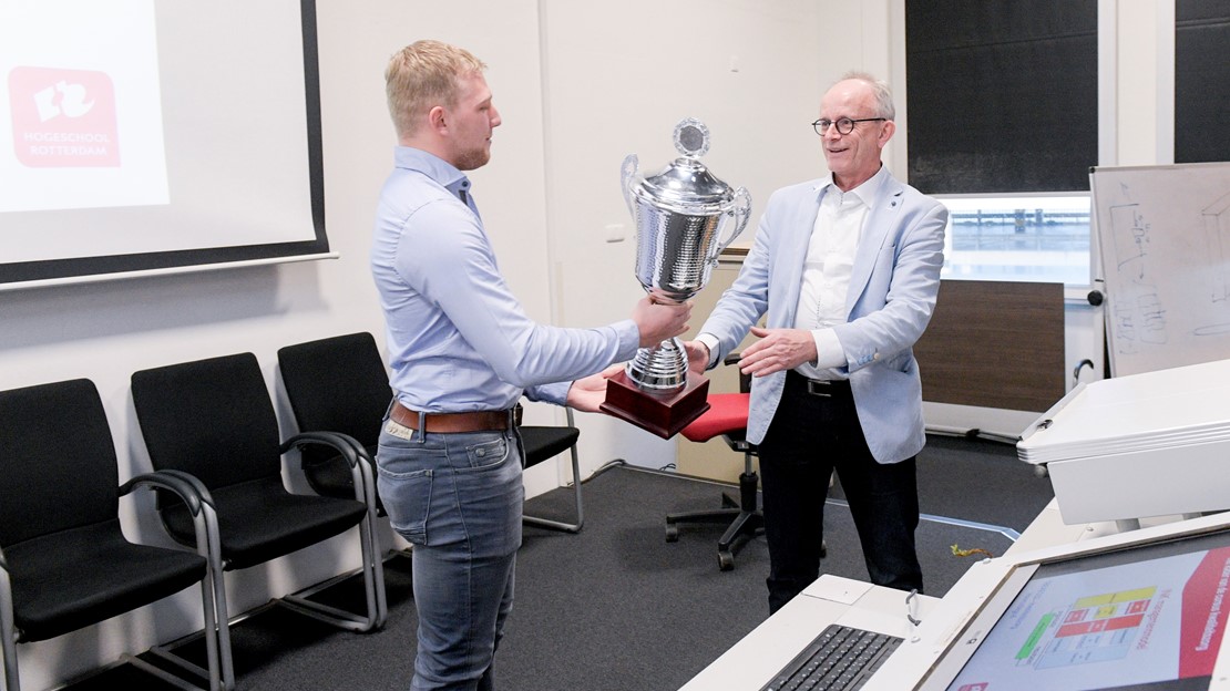 Student Thijs Luijsterburg overhandigt de prijs.
