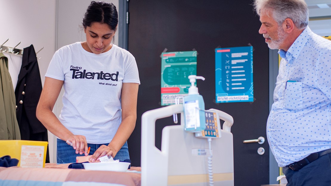 Docent Wim van den Berg kijkt hoe een van zijn studenten een injectie toedient.